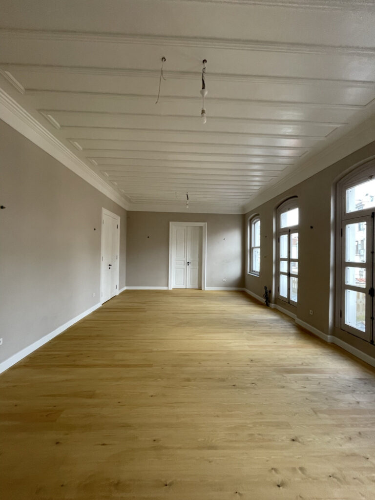 Beşiktaş Rum Okulu restorasyonu — kemerli pencereli uzun salon, restore edilmiş doğramalar ve masif ahşap zemin