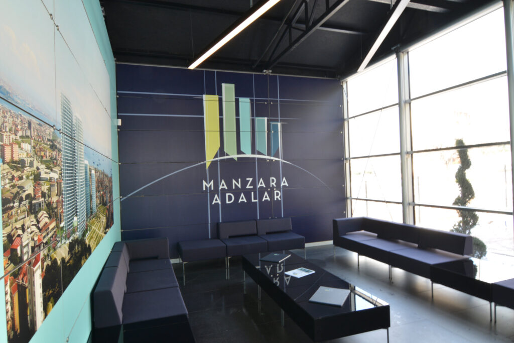 İş GYO Manzara Adalar satış ofisi — marka renkleriyle kurgulanan karşılama duvarı ve oturma alanı