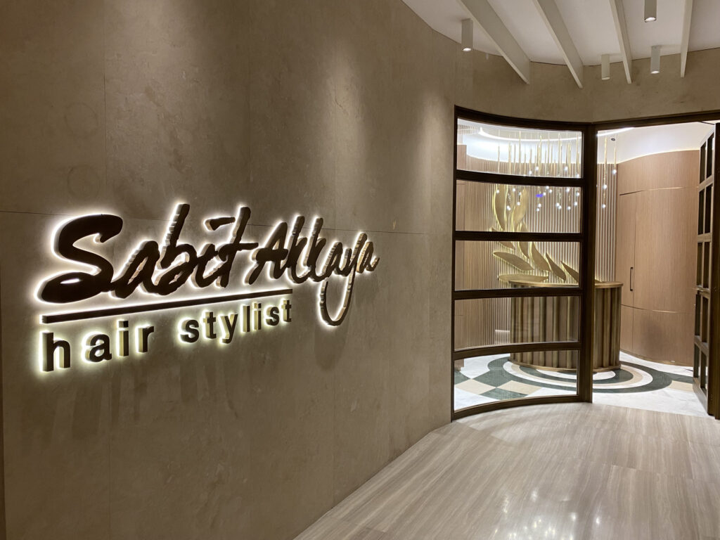 Sabit Akkaya Hair Stylist — giriş imzası ve travertan zemin detayı