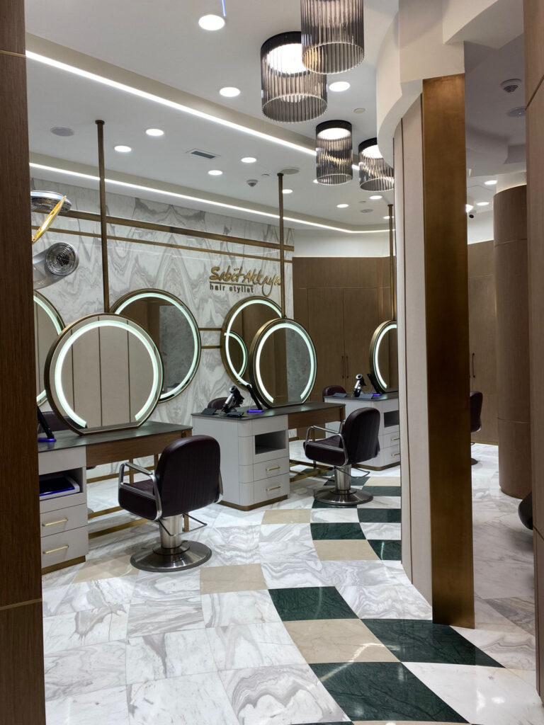 Sabit Akkaya Hair Stylist — kesim istasyonları, yuvarlak ışıklı aynalar ve damalı mermer zemin
